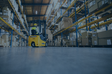 A forklift navigates a large warehouse full of pallets of goods
