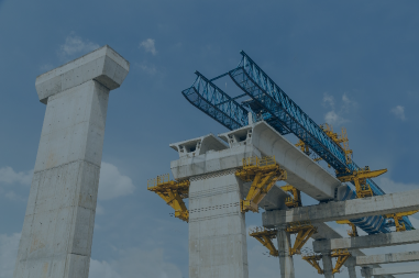 An overpass under construction. Large concrete pillars uphold a steel wireframe
